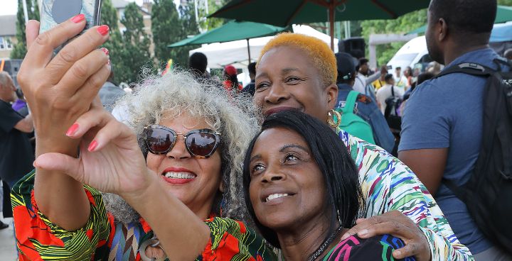 Three Black heritage women take a selfie at a local outdoor event