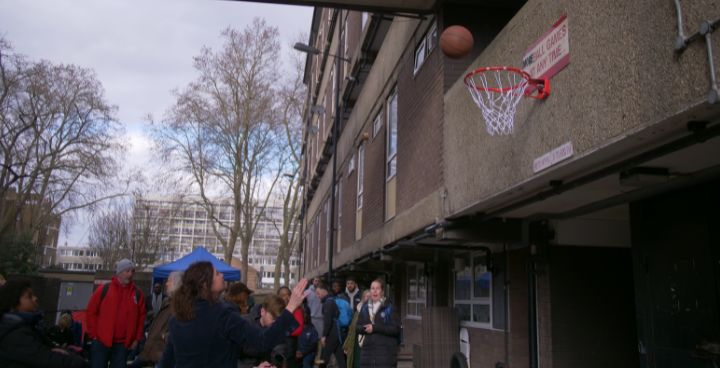 Woman throwing basket ball with crowd watching