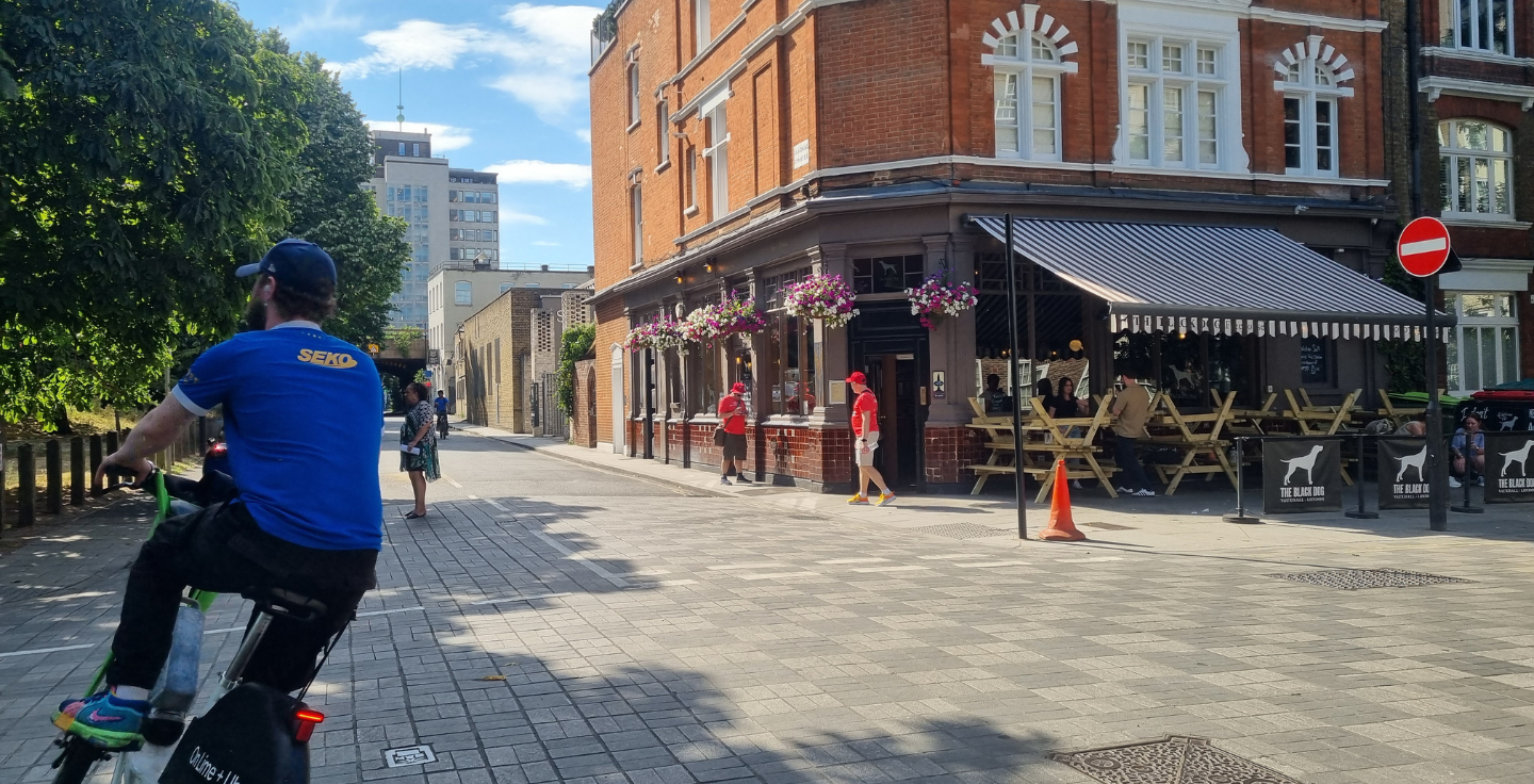 A road junction in Vauxhall, with pedestrians and cyclists passing by a historic pub