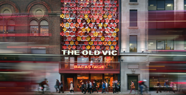 Photo of the new Old Vic Backstage building. The front of the building is covered with a colourful facade made up of metal 'flowers' in reds, yellows and oranges