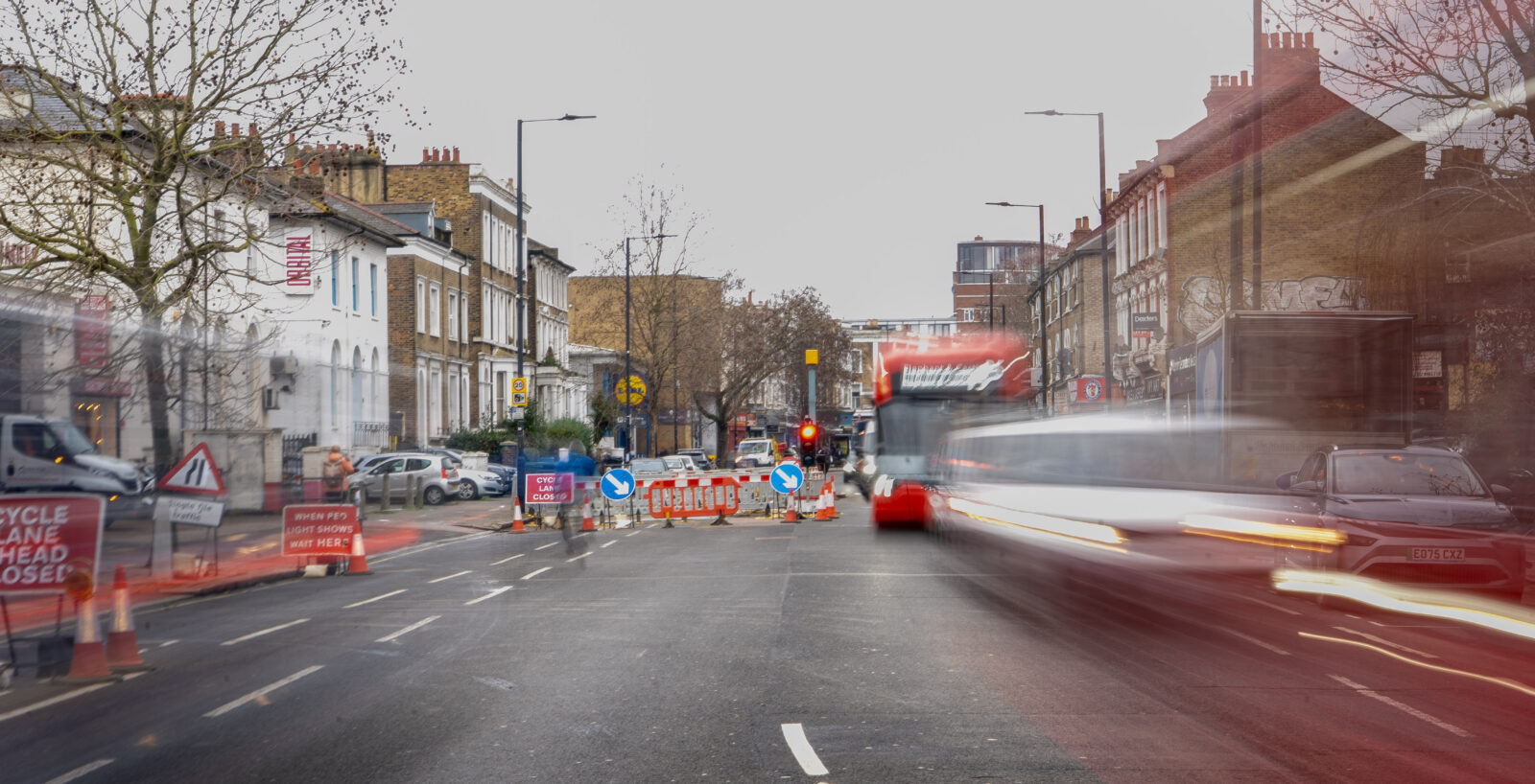 Long exposure photo of traffic moving along Acre Lane, Brixton, with roadworks and a bus visible