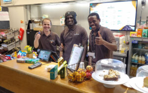 Colleagues in uniform give a thumbs up behind a counter